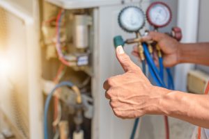 technician performing HVAC repairs and giving thumbs up