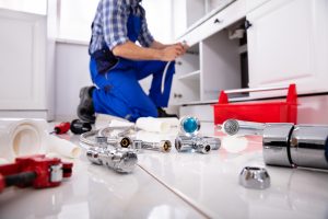 a plumber performing plumbing services underneath kitchen sink