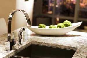 A kitchen sink and marble countertop.