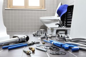 plumbing tools laying on the bathroom floor around a toilet that won't flush