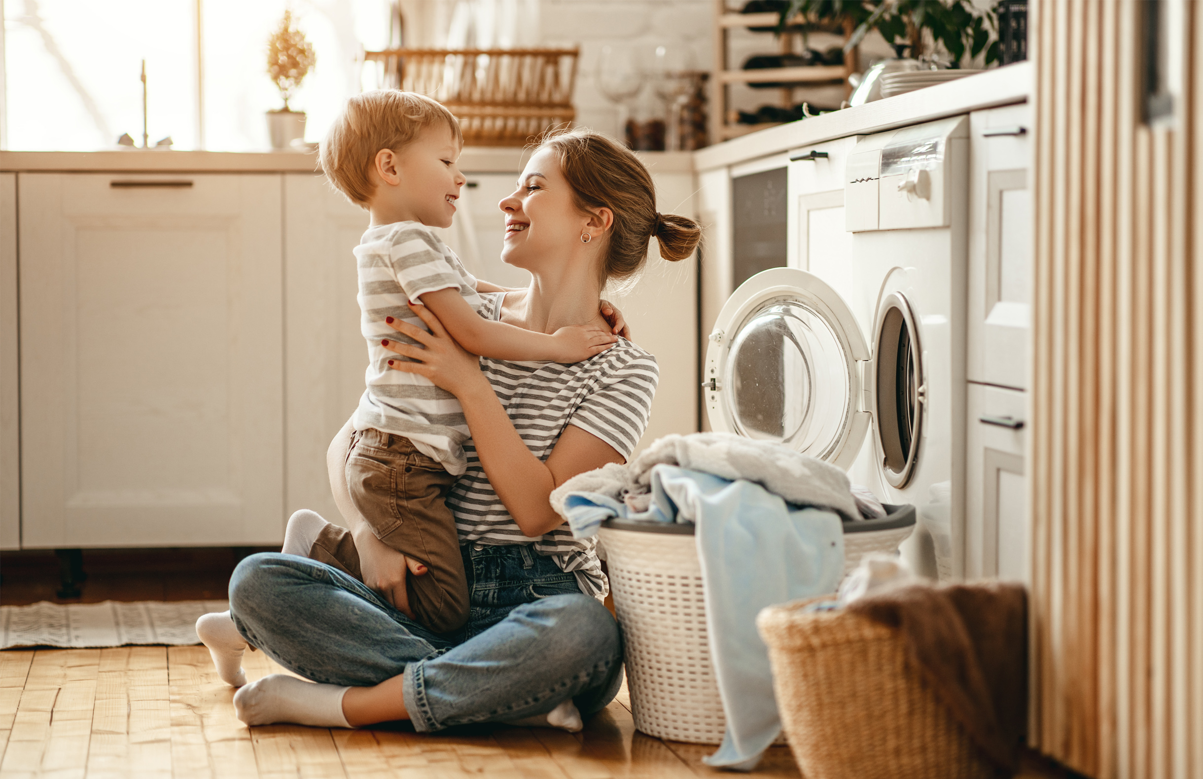 A mother holds her little boy in the laundry room of their home.