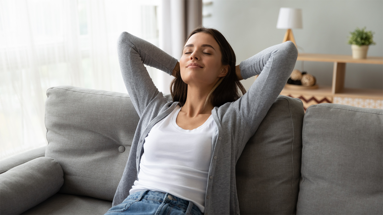 a woman comfortably relaxes on her couch after getting a dehumidifier installed in her home