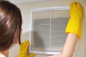 A woman changes a dirty HVAC air filter to improve residential indoor air quality.
